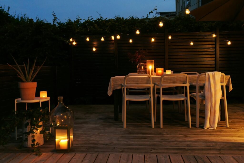 Outdoor dining setup with candles and string lights creates a cozy ambiance 